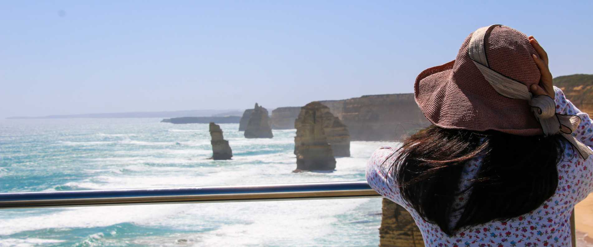 Woman holidng hat in front of Great Ocean Road